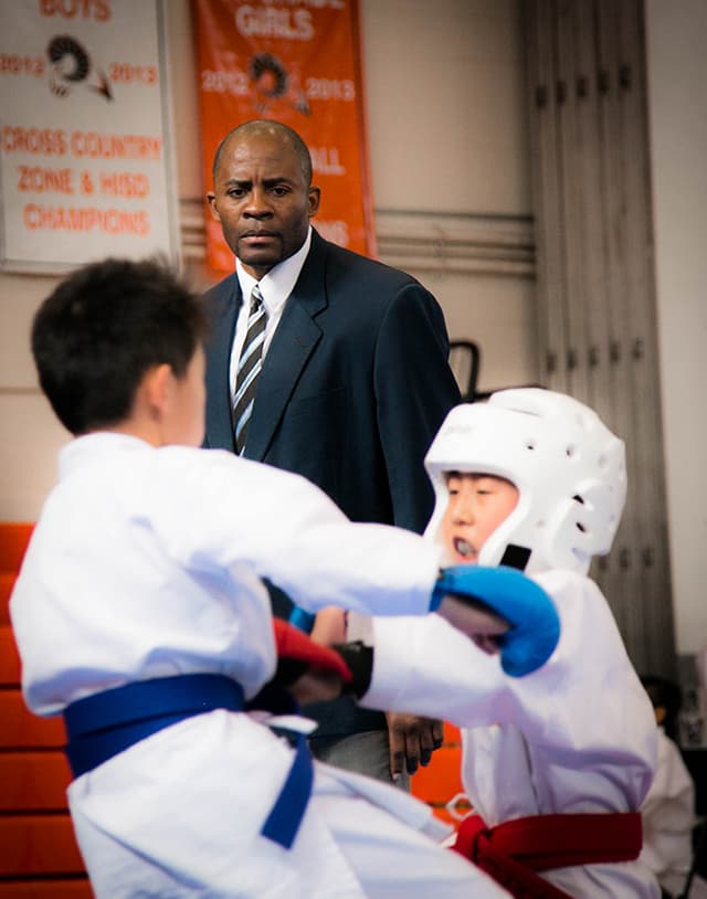 Sensei Alex Ndem judging karate tournament sparring